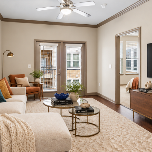 Spacious living room with modern staged furniture, large windows, and hardwood-style flooring at Stone Pointe Apartments in Woodbridge, VA