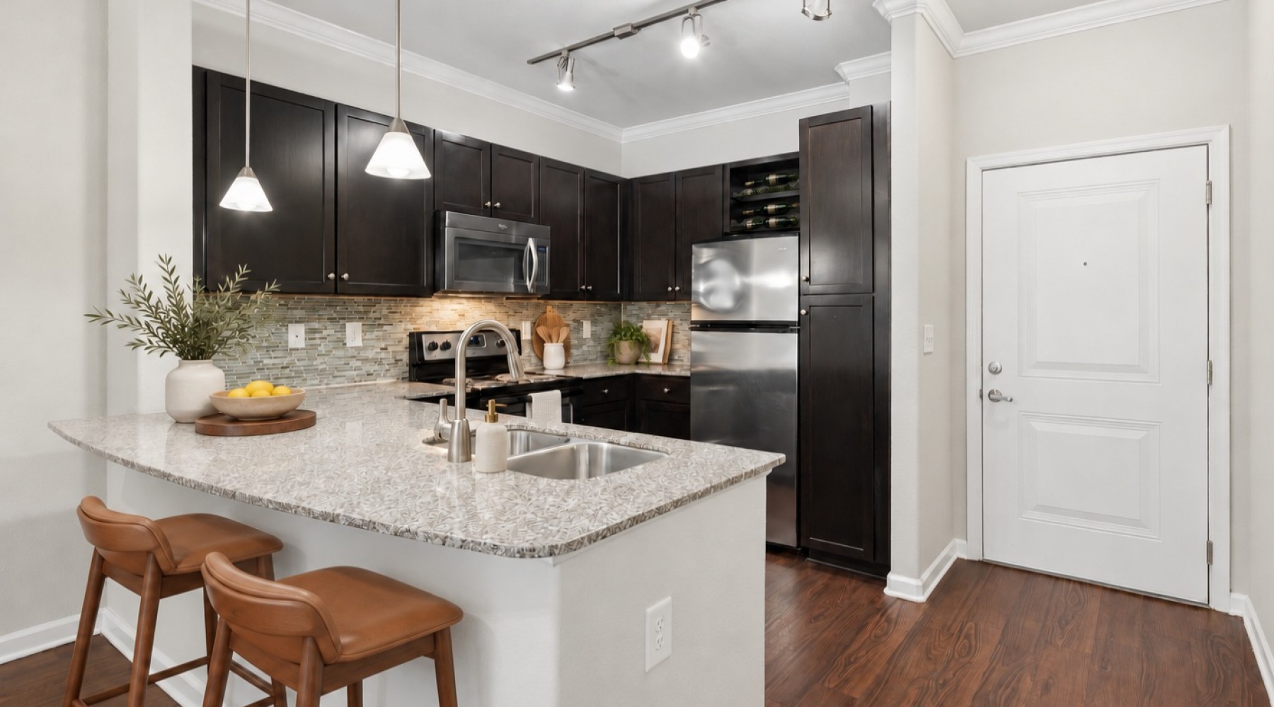 Open kitchen with granite breakfast bar, pendant lighting, bar stools and hardwood-style flooring at Stone Pointe Apartments in Woodbridge, VA