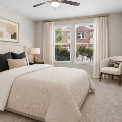 Bedroom with plush carpet, ceiling fan and large windows filling the room with natural light at Stone Pointe Apartments in Woodbridge, VA