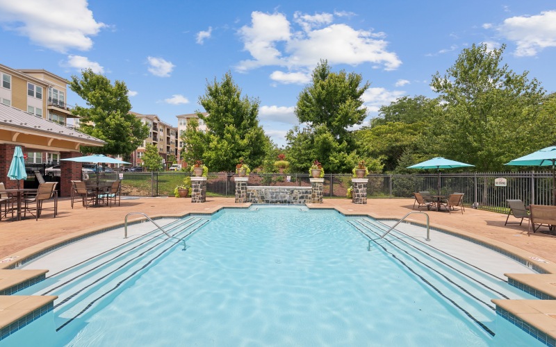 Resort-style outdoor swimming pool and sun deck surrounded by lounge seating and stone patio at Stone Pointe apartments.