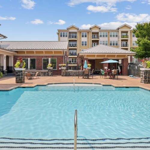Resort-style outdoor swimming pool and sun deck surrounded by lounge seating and stone patio at Stone Pointe apartments.
