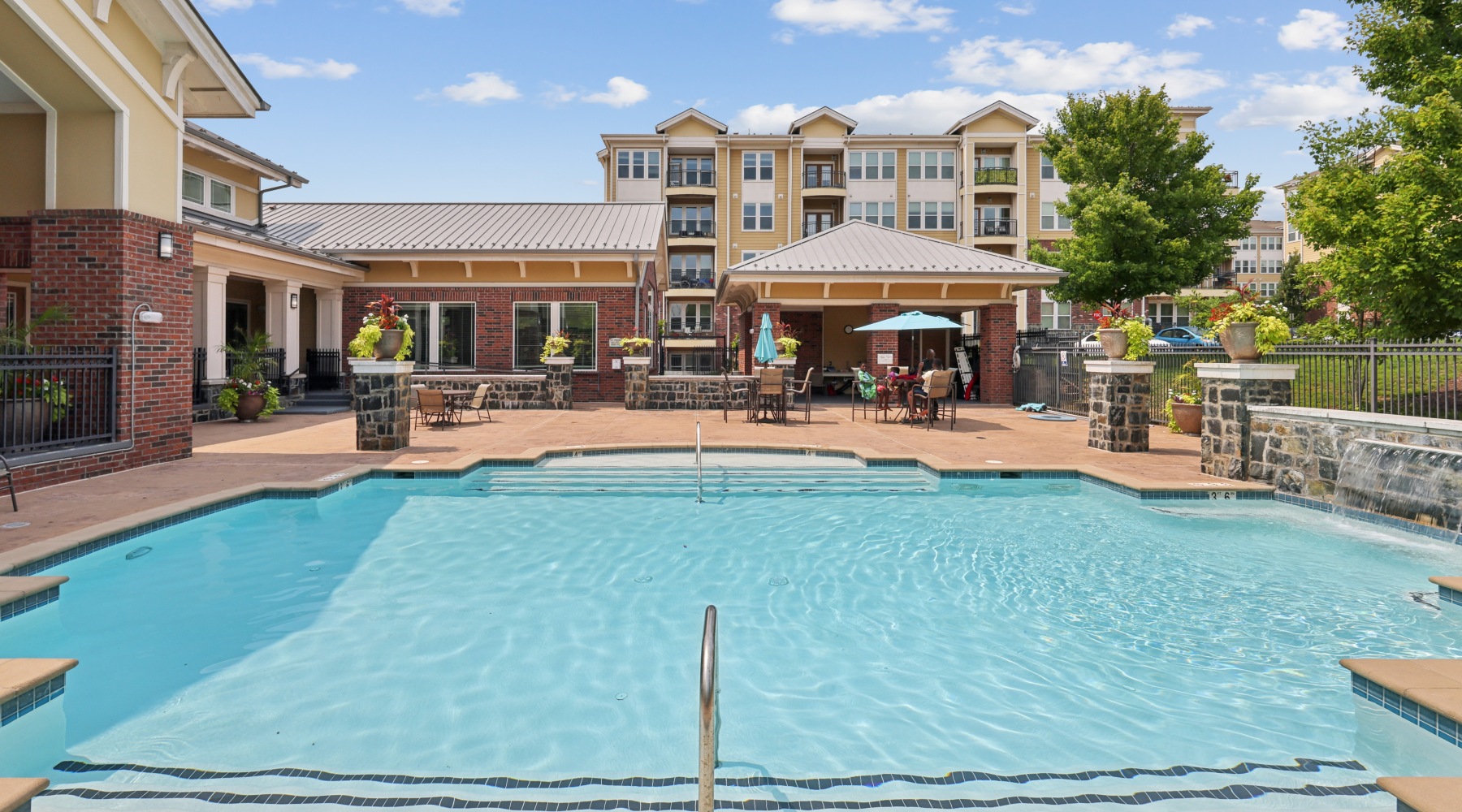 Resort-style outdoor swimming pool and sun deck surrounded by lounge seating and stone patio at Stone Pointe apartments.